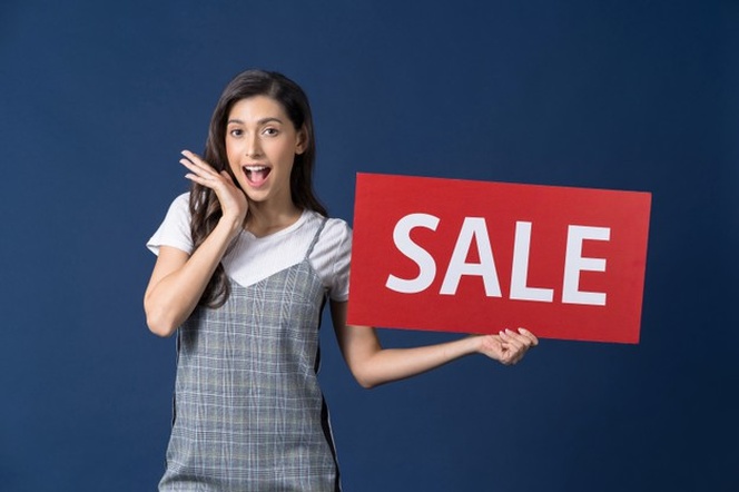Happy young asian woman holding sales banner and looking surprise to sales paper